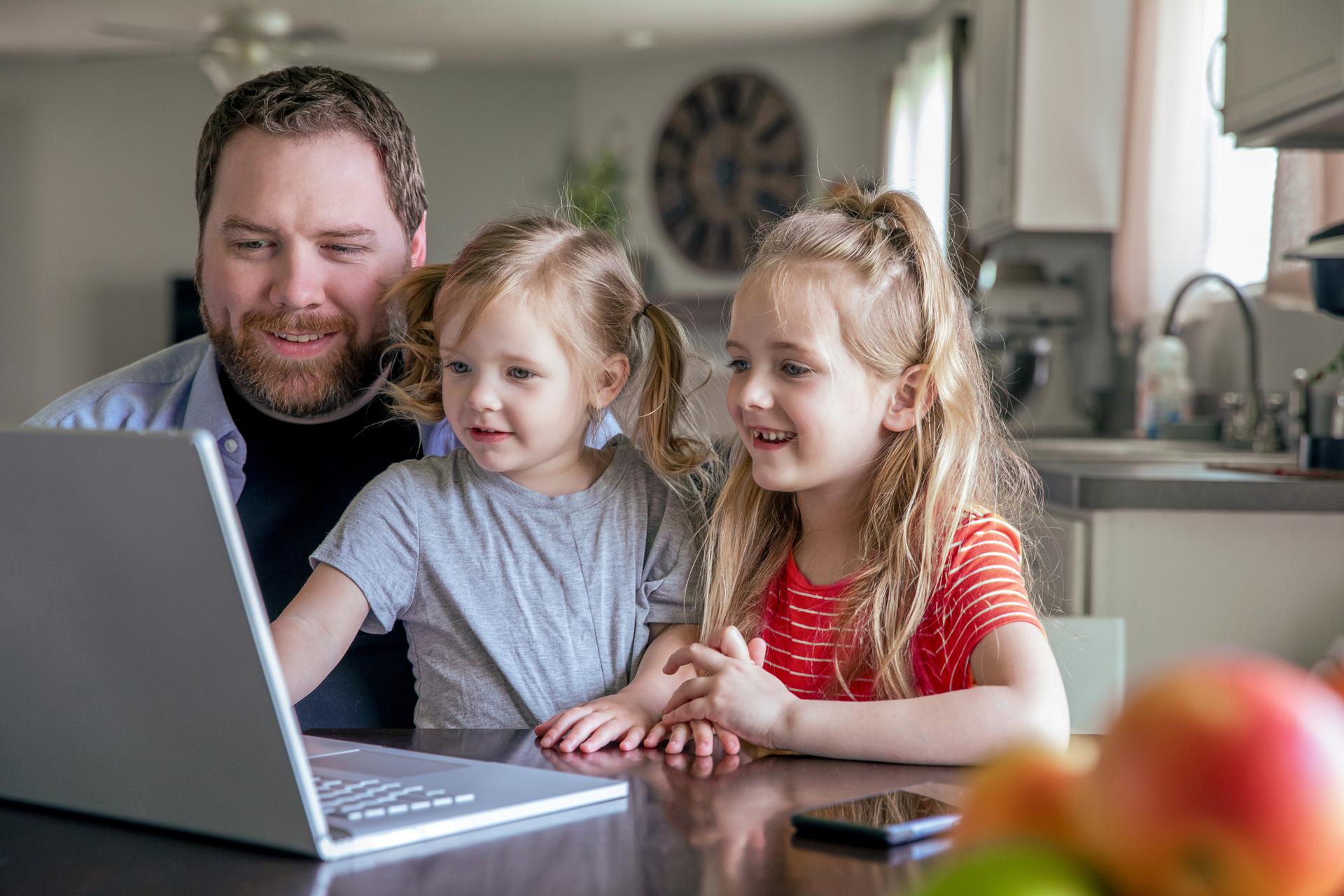 father with his daugthers watching laptop